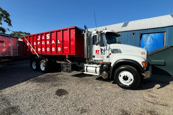 J&S Disposal's heavy-duty truck with a large red dumpster attachment, ready for house demolition and waste removal services, demonstrating the company's capability to handle large-scale debris and disposal needs.