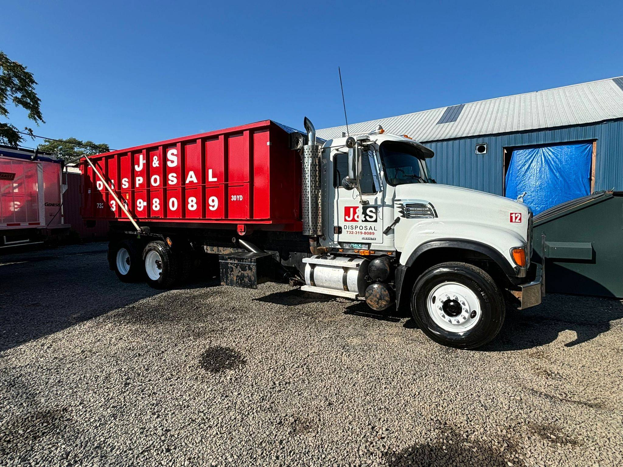 J&S Disposal's heavy-duty truck with a large red dumpster attachment, ready for house demolition and waste removal services, demonstrating the company's capability to handle large-scale debris and disposal needs.